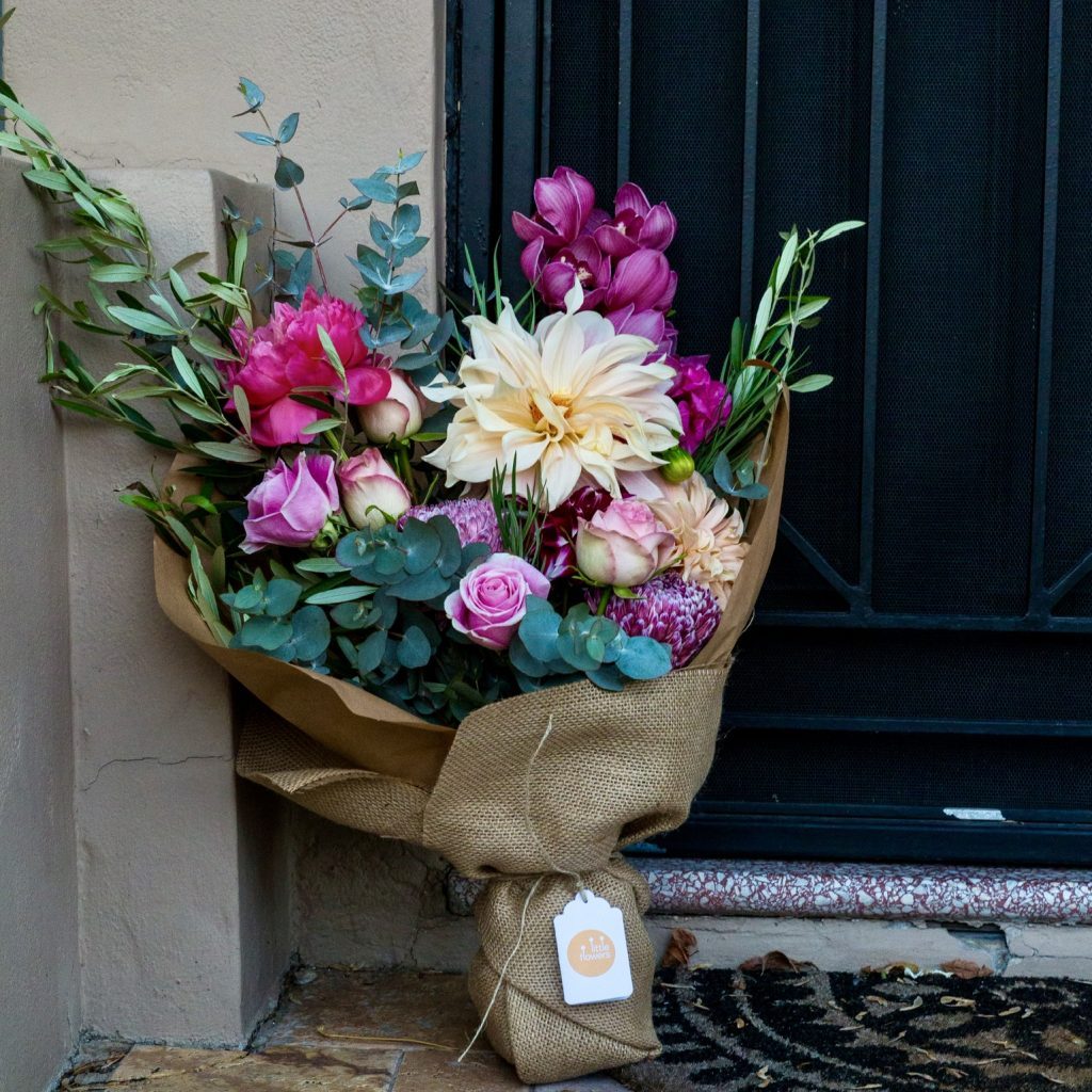 Bouquet of mixed seasonal flowers in hessian wrap left at a front door