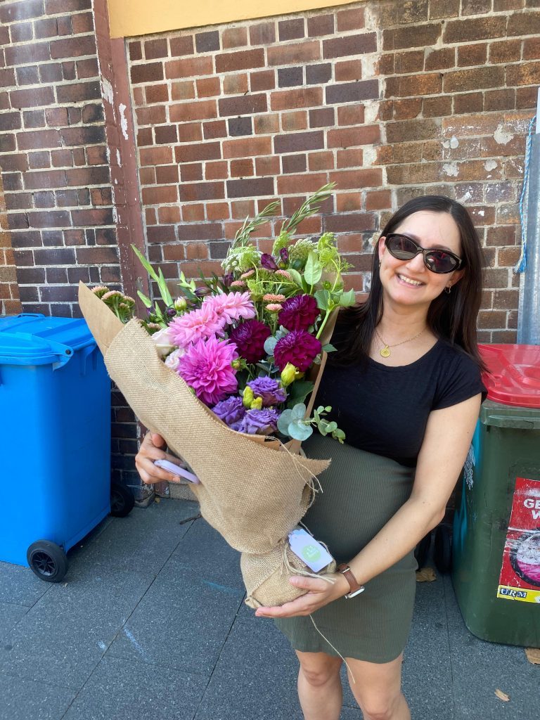 Surry Hills flower delivery - woman holding a colourful bouquet in front of a brick wall 