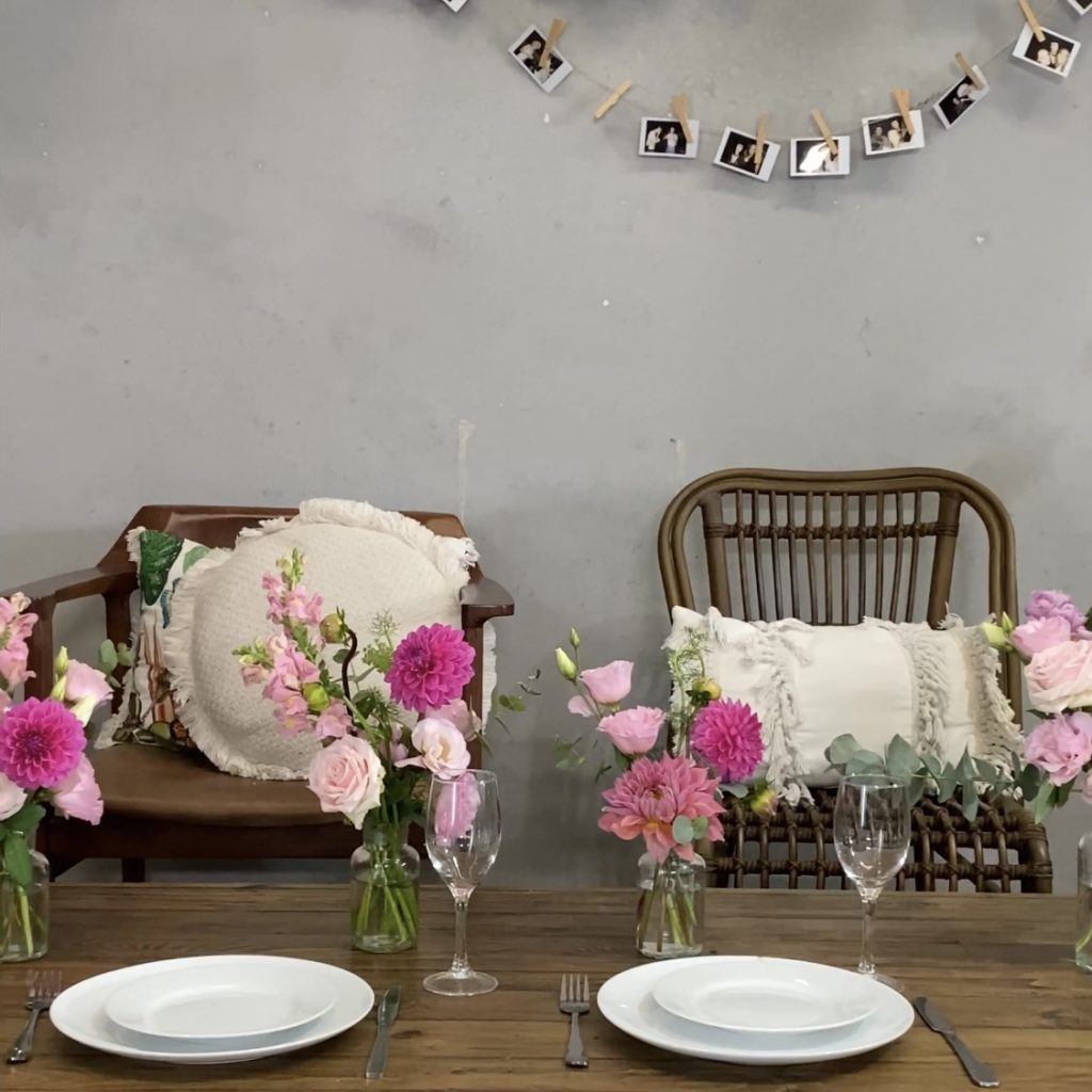 Pink flowers styled in vases on a dining table
