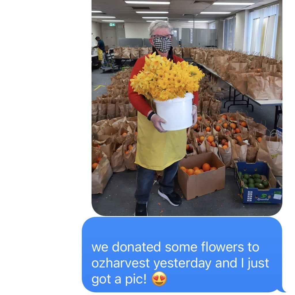 OzHarvest volunteer holding a bucket of bright yellow flowers