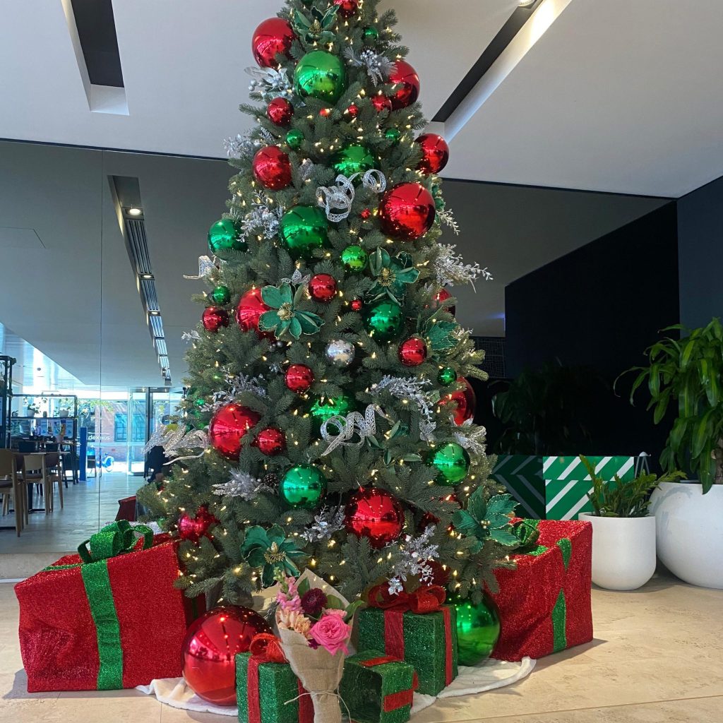 Christmas tree in Sydney CBD with presents underneath and a Little Flowers bouquet