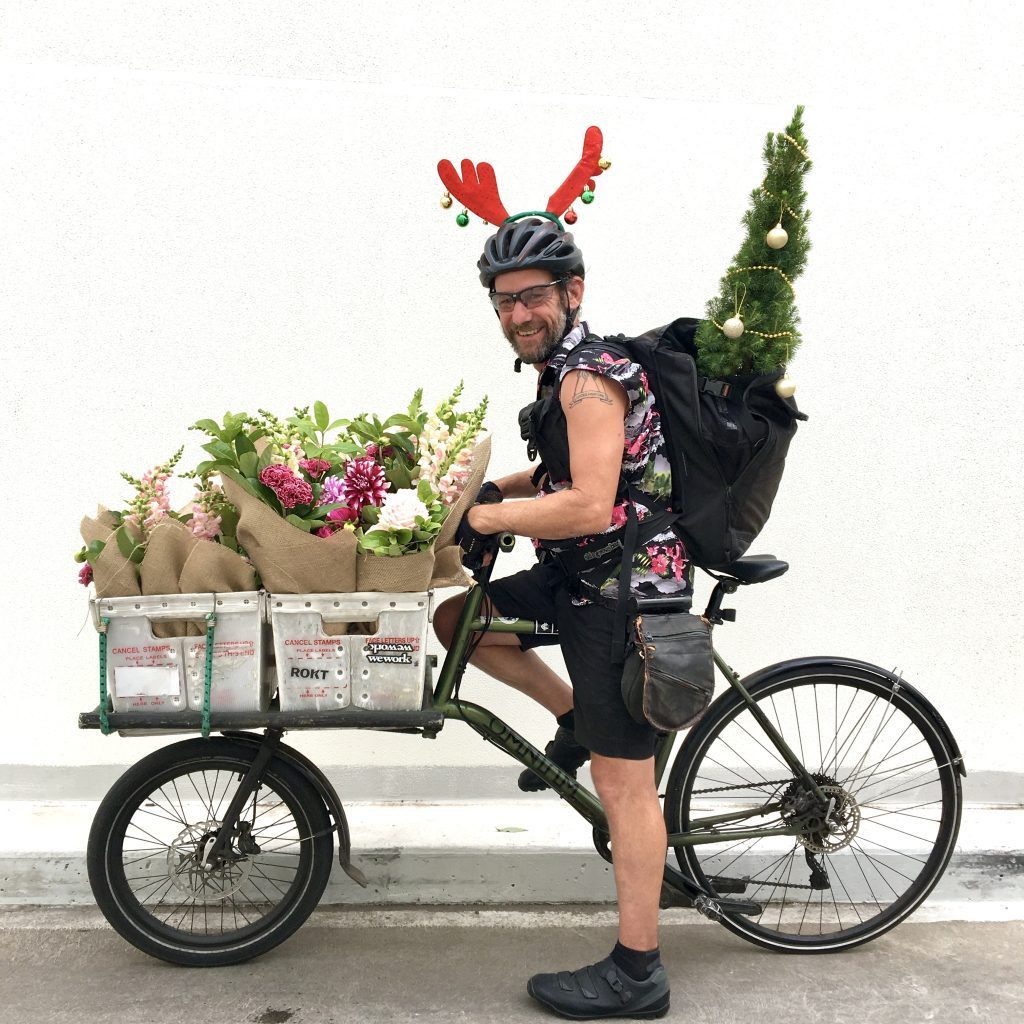 Little Flowers bike courier wearing reindeer antlers delivering a Christmas tree in Sydney