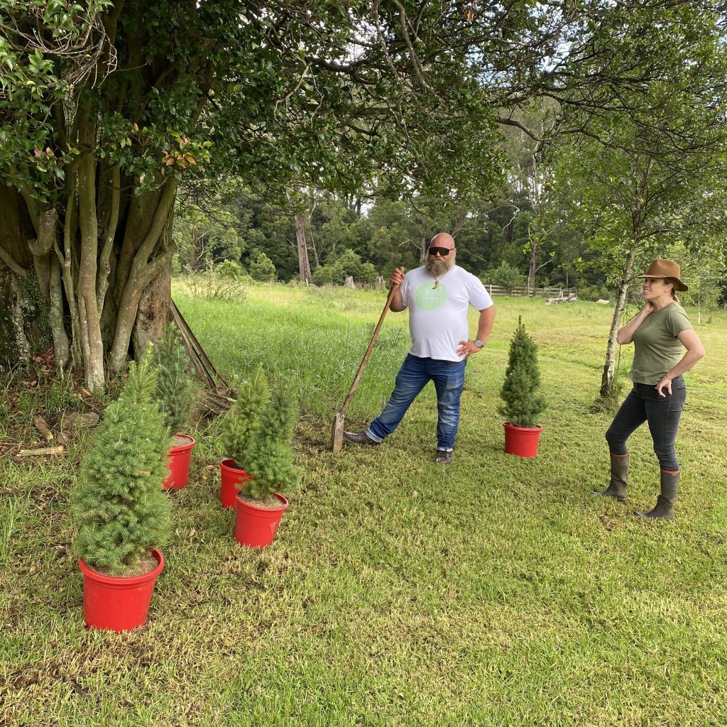 Farmer and Little Flowers team member standing together among young trees
